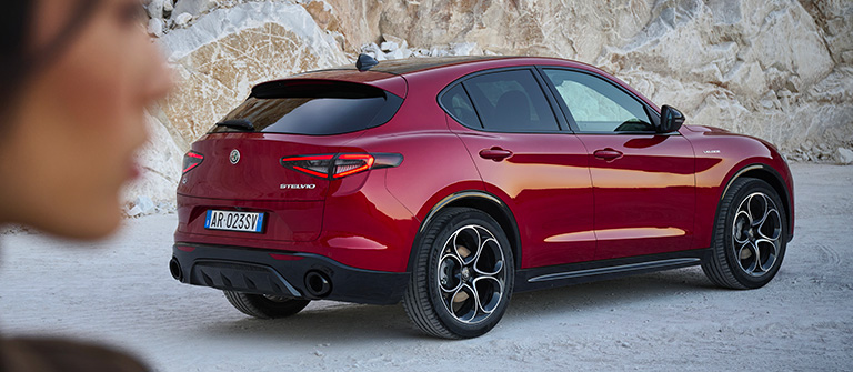 Profilen til en kvinne foran en rød Alfa Romeo Stelvio